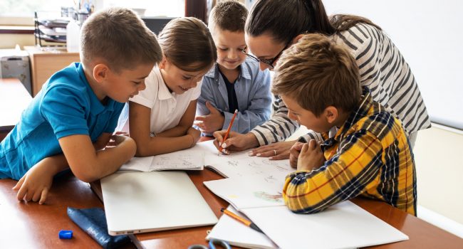 Female,Teacher,Helps,School,Kids,To,Finish,They,Lesson.they,Sitting
